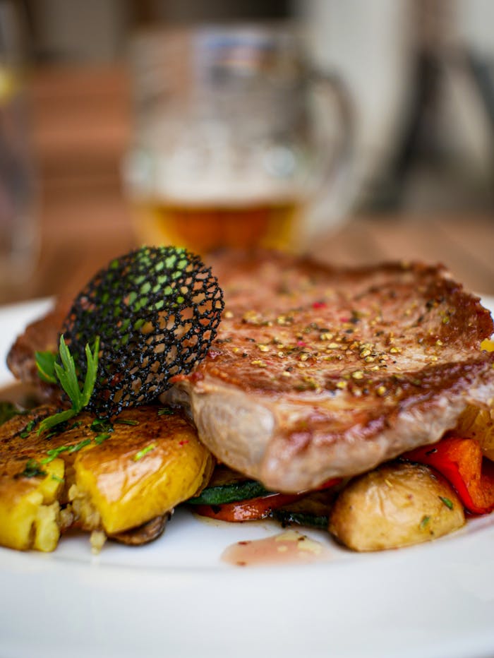 Close-up of a delicious grilled steak served with roasted vegetables on a gourmet plate.