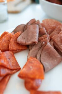 Close-up of a charcuterie platter featuring sliced meats on a white plate, perfect for parties.